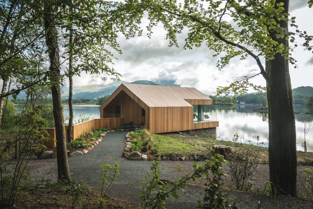 A picturesque landscape of Derwentwater, nestled amongst the trees and at the edge of the lake, a beautiful wooden clad boat house.